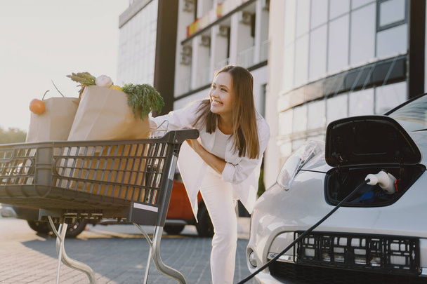Woman charging electro car at the electric gas station - Valokuva, kuva