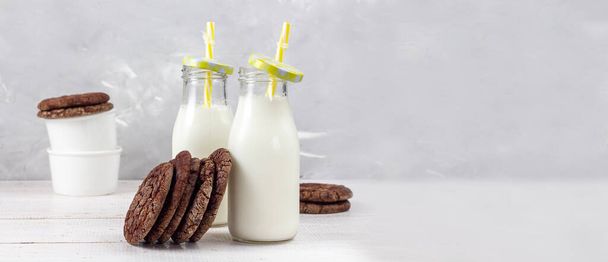 Köstliche frische Milch auf altem Holzgrund. Ein Krug Milch und eine Flasche Milch. Kekse. Banner. Kopierraum - Foto, Bild