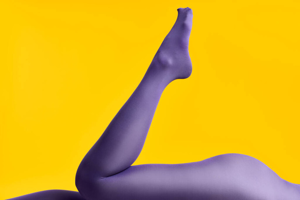 Legs of beautiful young woman in bright tights lying on yellow background - Fotografie, Obrázek