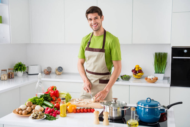 Portrait of attractive cheerful skilled guy cooking tasty yummy meal boiling sause spending day at light white kitchen home indoors - Fotoğraf, Görsel