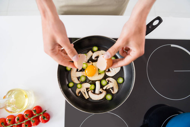 Cropped photo cooking man adding sliced vegetables mushrooms on frying pan making omelette - Foto, imagen