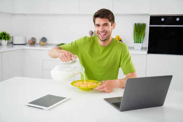 Portrait of attractive cheerful guy preparing fresh fast lunch eating pouring organic milk at home kitchen indoors - Photo, Image