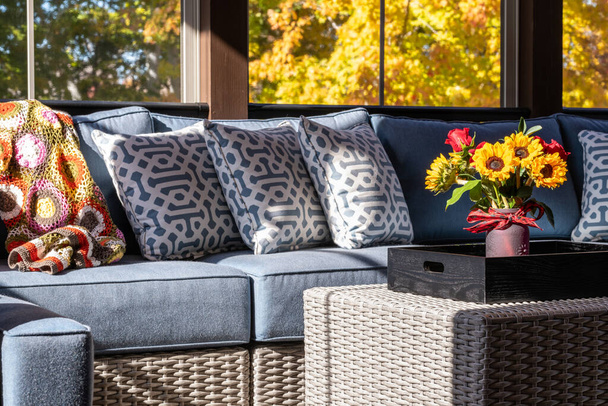 Cozy screened porch with contemporary furniture and flower bouquet in a vase, autumn leaves and woods in the background. - Photo, Image