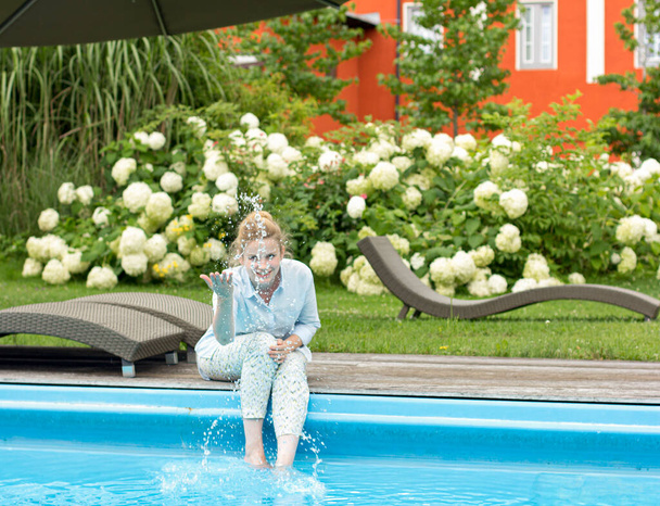 Young beautiful woman is resting on the territory of the hotel by the pool - Φωτογραφία, εικόνα
