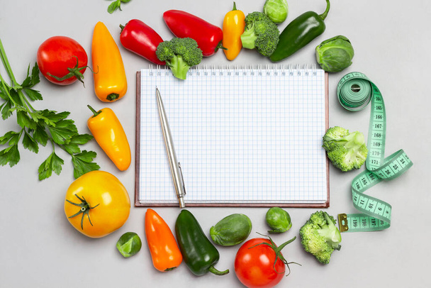 Notepad and pen, measuring tape and vegetables on table. Flat lay. Gray background - Foto, immagini