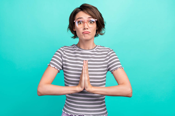 Photo of please young brunette lady hold hands wear spectacles striped t-shirt isolated on teal color background - Фото, зображення