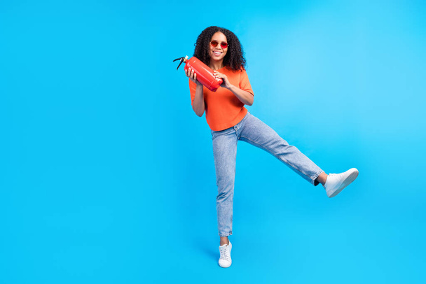 Full size photo of young african woman happy positive smile hold fire extinguisher safety isolated over blue color background - Фото, изображение
