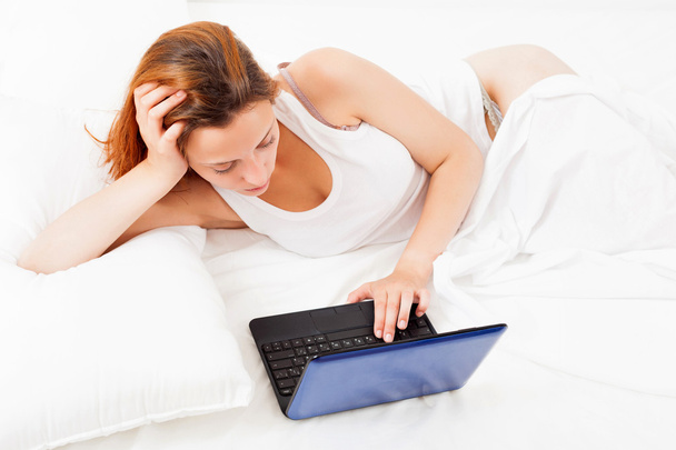 Girl with laptop lying in her bed - Fotoğraf, Görsel