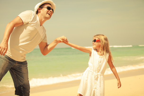 isä ja tytär leikkivät rannalla päivällä
 - Valokuva, kuva