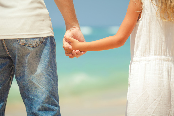 padre e hija de pie en la playa durante el día
 - Foto, Imagen