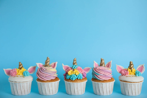 Sok aranyos édes unikornis cupcakes világoskék háttér - Fotó, kép