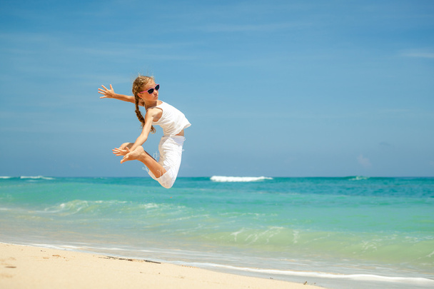 Teenie-Mädchen springt im Sommerurlaub am Strand am blauen Meer - Foto, Bild