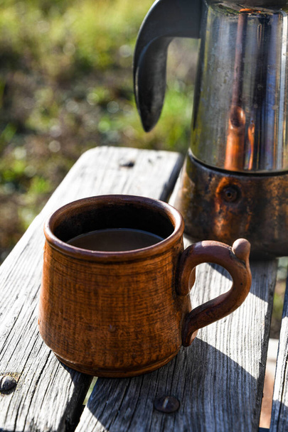 間欠泉のコーヒーメーカーで調製された庭の外のコーヒーとセラミックカップ. - 写真・画像