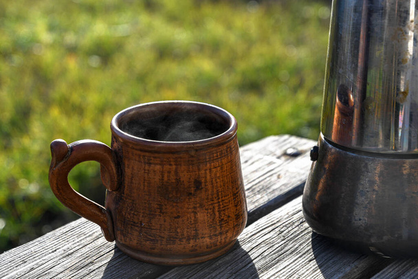 Taza de cerámica con café al aire libre en el jardín preparado en una cafetera géiser. - Foto, Imagen