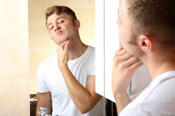 Young man shaving his beard in bathroom - 写真・画像