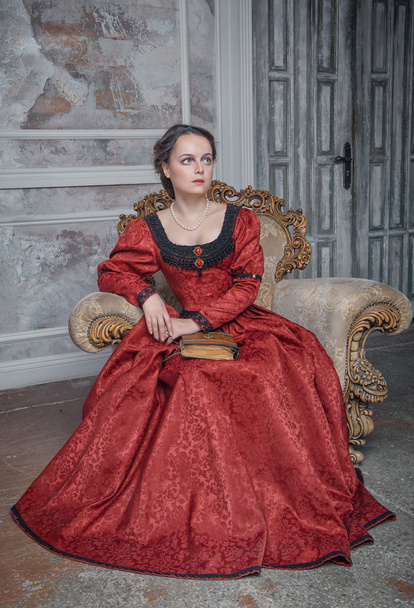 Beautiful woman in medieval dress on the armchair - Photo, Image