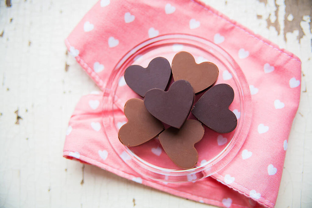 czekoladowe cukierki w kształcie serca na talerzu z różowym ręcznikiem - Zdjęcie, obraz