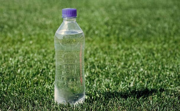 water bottle on green grass. sport and fitness. healthy drink. global environment conservation. plastic garbage need recycle. fresh and clean. feel thirsty. pure natural drinking. mineral vitamins - Foto, afbeelding