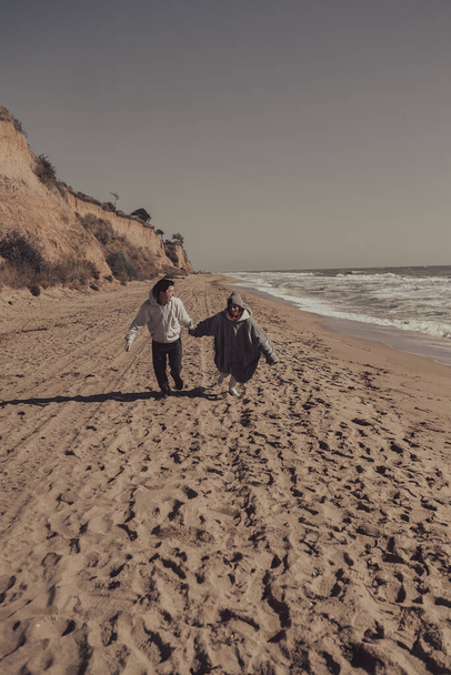 Uomo e donna si divertono a vicenda, corrono lungo la riva del mare - Foto, immagini