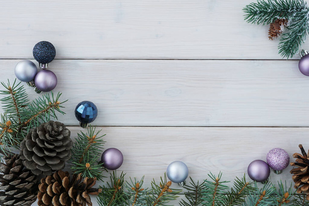 Bovenaanzicht van groene sparren takken en kegels, kerstballen op witte houten plank achtergrond, veel copyspace. Kerstconcept                                          - Foto, afbeelding