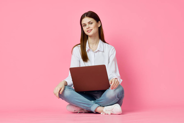 woman sitting on floor with laptop shopping entertainment pink background - Foto, afbeelding