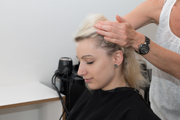 Chica rubia recibiendo un masaje en la cabeza en una peluquería
 - Foto, imagen