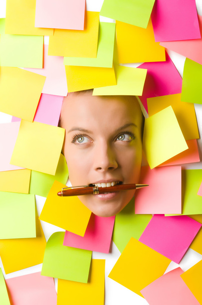 Woman with many reminder notes and pen in the mouth - Photo, Image