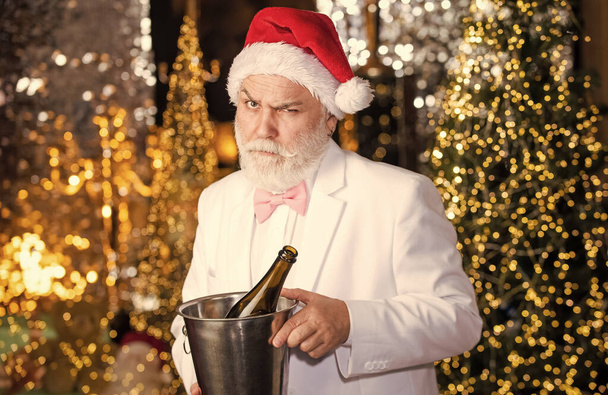 幸せな髭の男だ。男サンタ帽子スパークリングワインを飲む。冬休みだ。サンタはシャンパンを飲む。冬のお祝い。新年の贈り物。冬の伝統。大人のパーティーのコンセプト。アルコールだ。メリークリスマス - 写真・画像