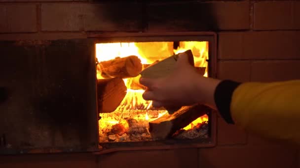 A kéz tűzifát helyez a tűzhely kemencéjébe, lángnyelveket a rusztikus tűzhelyre. - Felvétel, videó