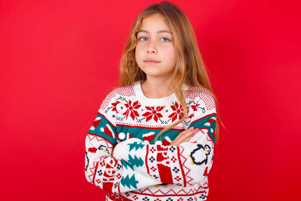 Я впевнений, що серйозна спокійна красива дівчина в різдвяному светрі стоїть зі складеними руками. Показує професійну позу вібе у наполегливій позі. - Фото, зображення