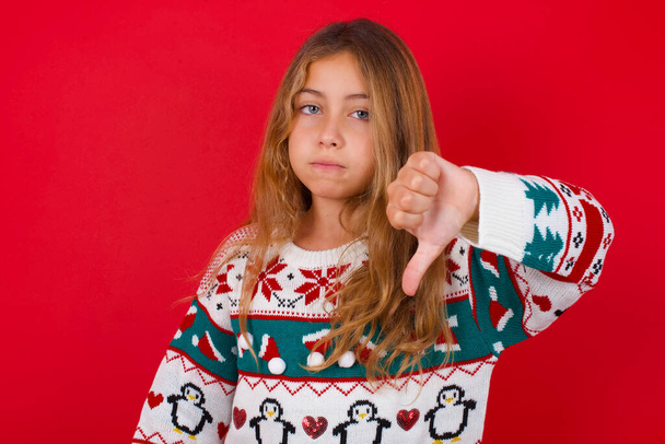  beautiful girl wearing sweater   looking unhappy and angry showing rejection and negative with thumbs down gesture. Bad expression. - Photo, Image