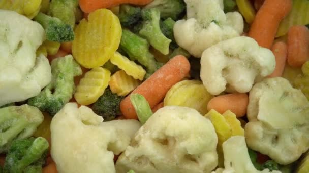 Świeże mrożone warzywa na wirującym tle, zdrowa żywność lub dieta dla wegetarian i wegan, mrożone kalafiory, brokuły i marchewki dla niemowląt - Materiał filmowy, wideo