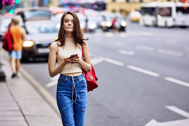 Mujer de 18 años escucha música con smartphone y auriculares. - Foto, imagen