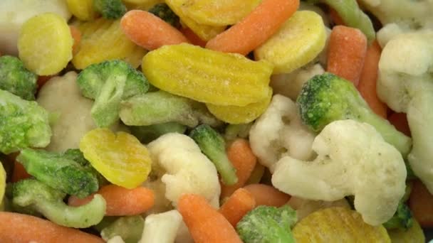Świeże mrożone warzywa obracające się w tle, zdrowa żywność lub dieta dla wegetarian i wegan, mrożone kalafiory, brokuły i marchewki dla niemowląt - Materiał filmowy, wideo