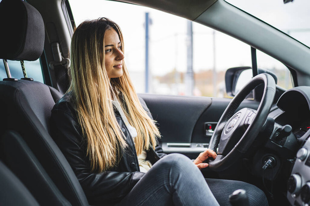 Young adult one caucasian woman sitting in car waiting side view copy space - Photo, Image