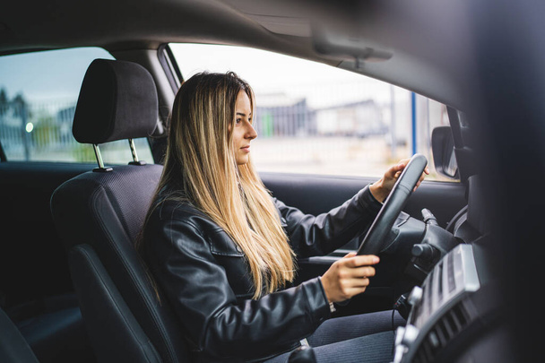 Mladý dospělý jeden kavkazský žena řízení auto čeká při držení volant při pohledu na silnici pohled žena řidič kopírovat prostor skuteční lidé - Fotografie, Obrázek