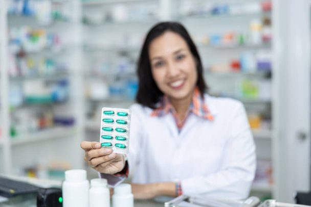 green vitamin capsules in holding hand of thai female doctor in pharmacy Thailand - Zdjęcie, obraz