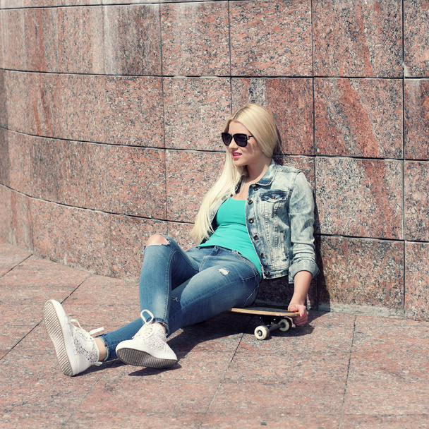 Fille en veste assis sur un skateboard
 - Photo, image