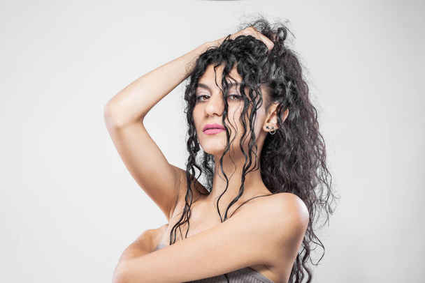 Beautiful brunette girl with long wet hair, studio portrait. Serious face expression. - Fotó, kép