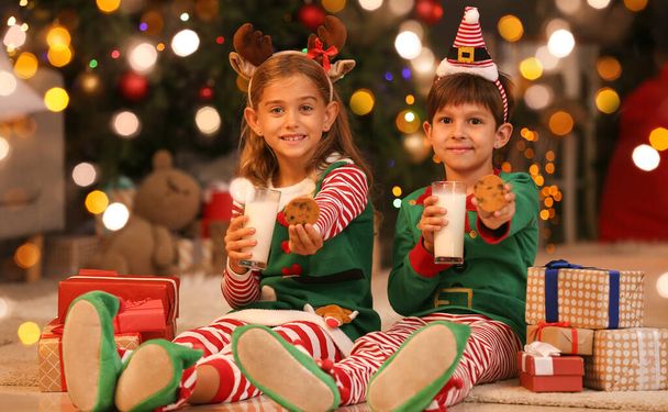 Słodkie małe elfy pijące mleko z ciasteczkami w domu w Wigilię - Zdjęcie, obraz