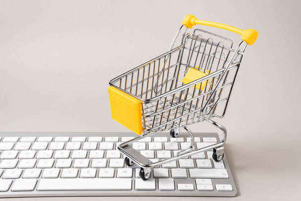 miniature shopping cart on a computer keyboard on gray background with copy space - Foto, immagini