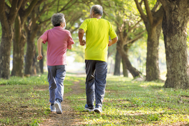Rear view of Senior couple in face mask and jogging in the park - Photo, Image