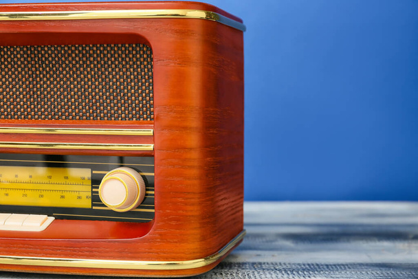 Retro radio receiver on table against color background - Photo, Image
