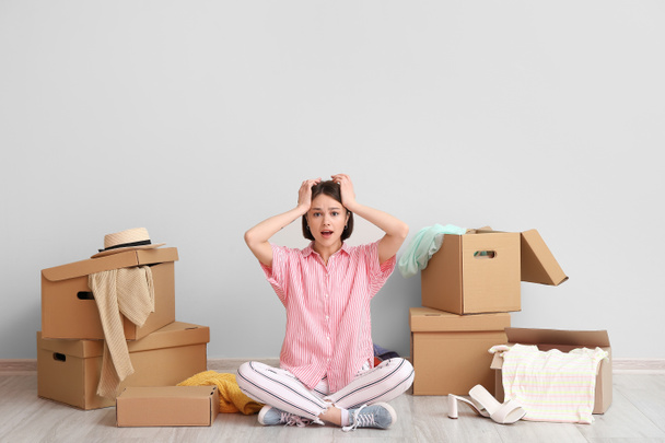 Stressato giovane donna con scatole armadio e cose vicino parete luminosa - Foto, immagini
