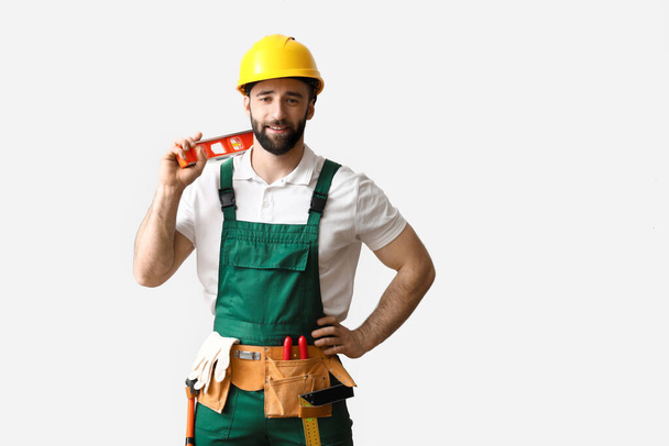 Rakennustyöntekijä kypärässä rakentajan tasolla kevyellä taustalla - Valokuva, kuva