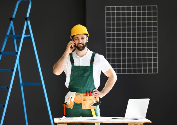 Stavební dělník mluví mobilním telefonem na pokoji - Fotografie, Obrázek