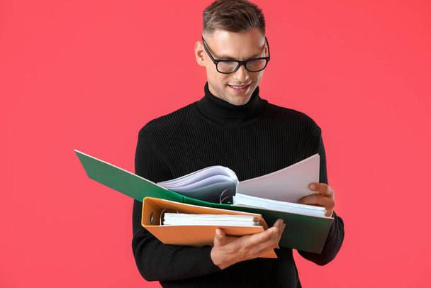 Young man with folders on color background - Foto, afbeelding