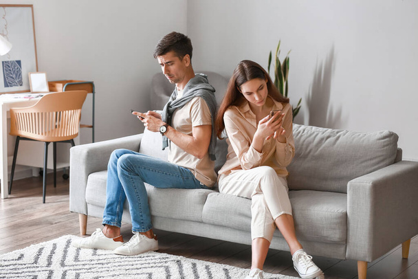 Young couple using mobile phones at home - Fotoğraf, Görsel