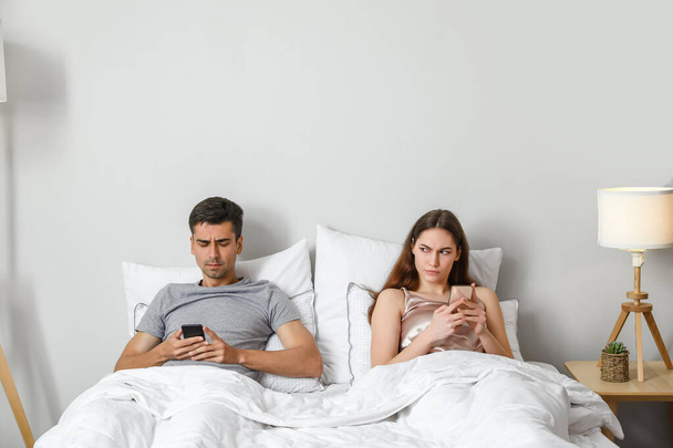 Junges Paar benützt Handy nach Streit im Schlafzimmer - Foto, Bild