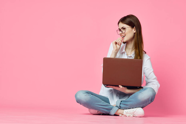 woman sitting on floor with laptop shopping entertainment pink background - Фото, зображення